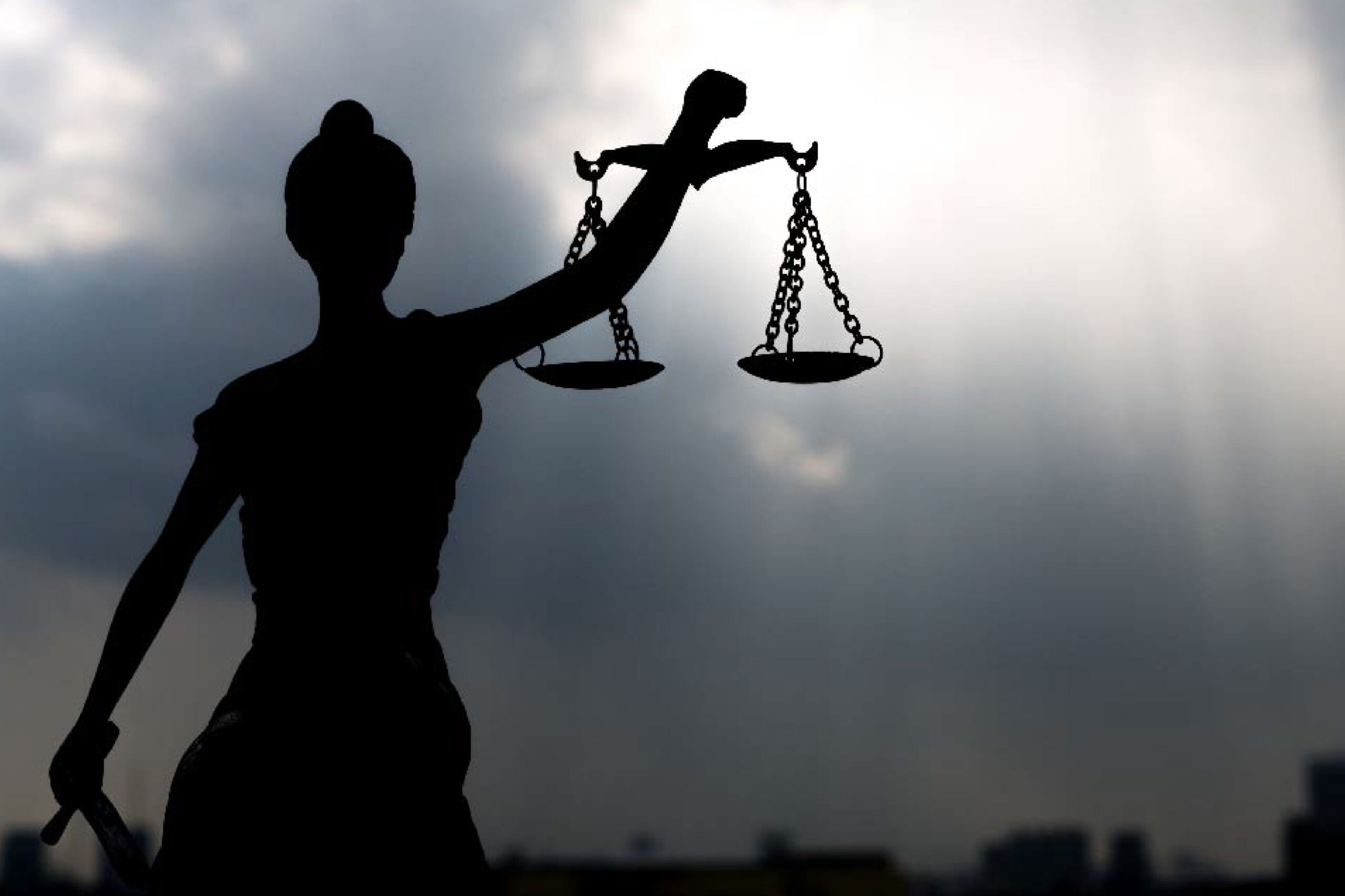 a silhouette of a statue of the scales of justice
