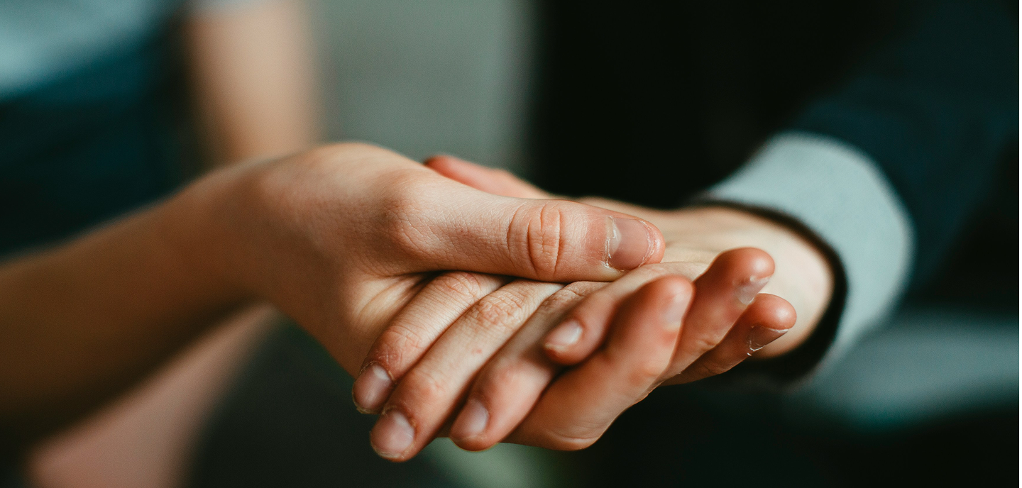 Mental health counselor holding a patient’s hand.