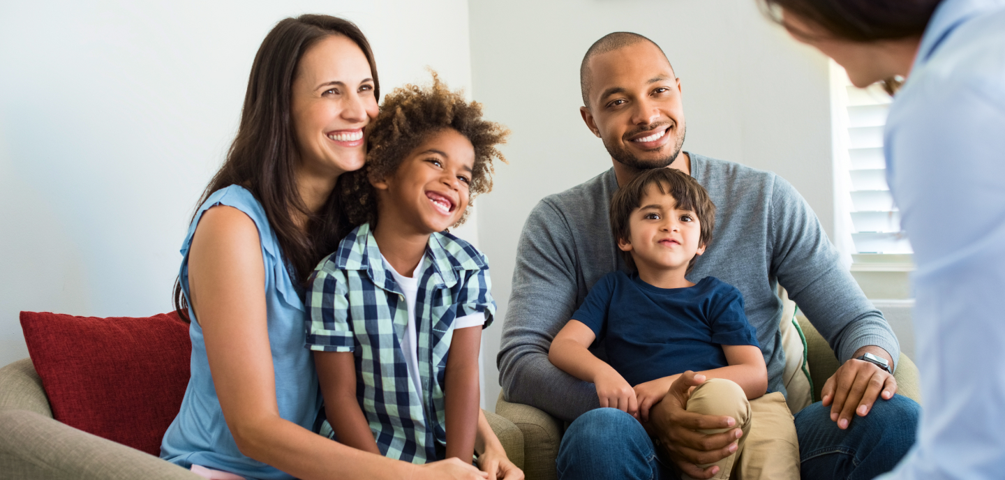 Family sitting together and smiling as they speak with a professional counselor.