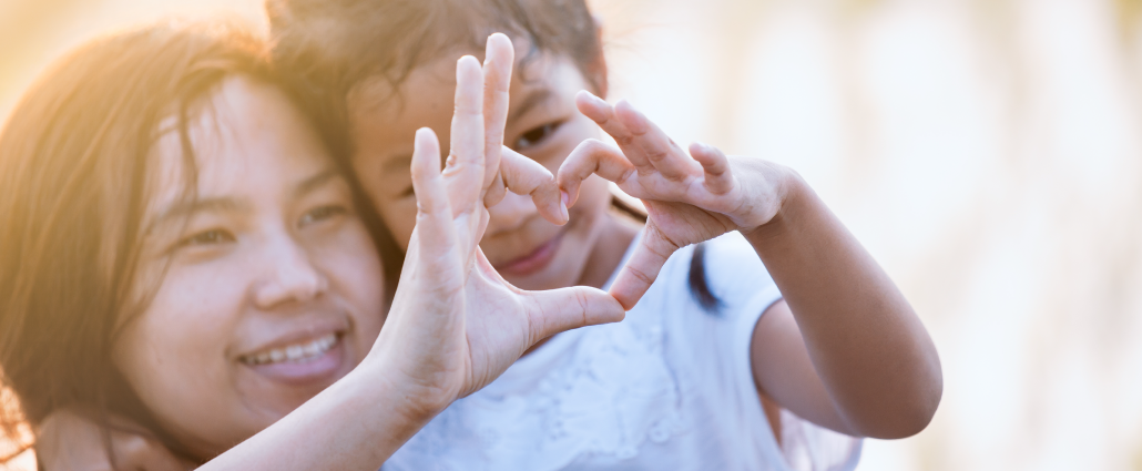 Mother and child putting their hands together to form the shape of a heart.