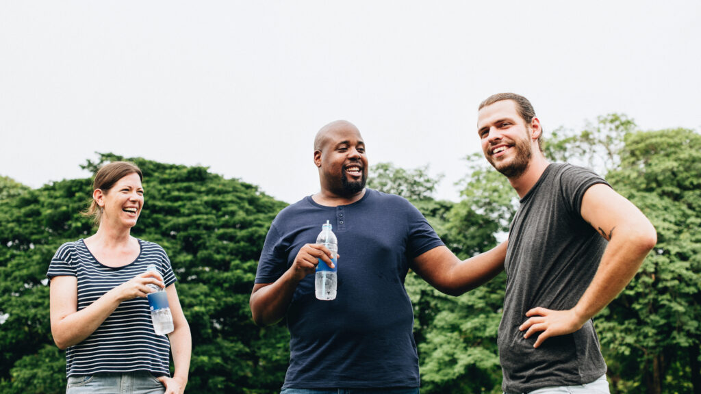 Friends holding a bottle of water and chatting in the park